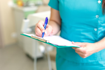 dentist, recording in document, on background dental clinic selective focus