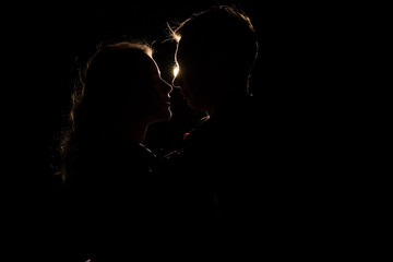 black background, silhouette of couples, heads, between them a light, a ray of light unfinished kiss. the beginning of a kiss.