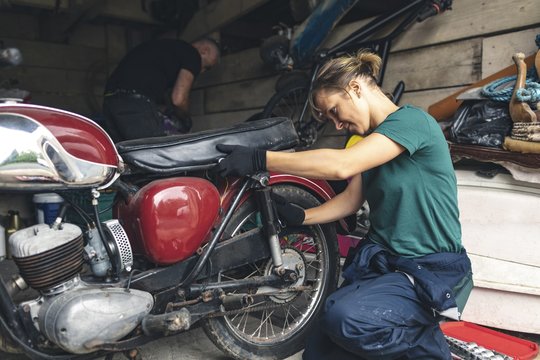 Mechanics repairing motorcycle in workshop