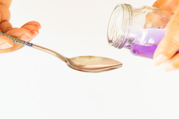 Healthcare, people and medicine concept , Hand on hold pouring medication or antipyretic syrup from...
