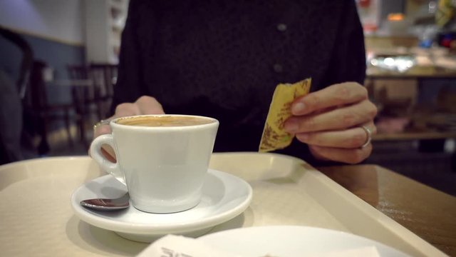 Female Hand mixing suggar into coffee latte with metallic spoon