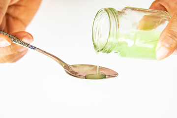 Healthcare, people and medicine concept , Hand on hold pouring medication or antipyretic syrup from...