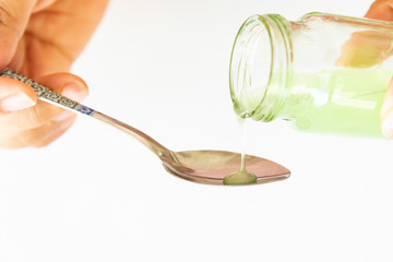 Healthcare, people and medicine concept , Hand on hold pouring medication or antipyretic syrup from...