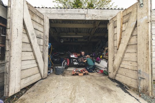 Mechanic repairing motorbike in garage - Powered by Adobe