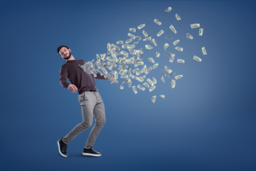 A bearded man almost falls back with many dollar banknotes flying out of his chest.