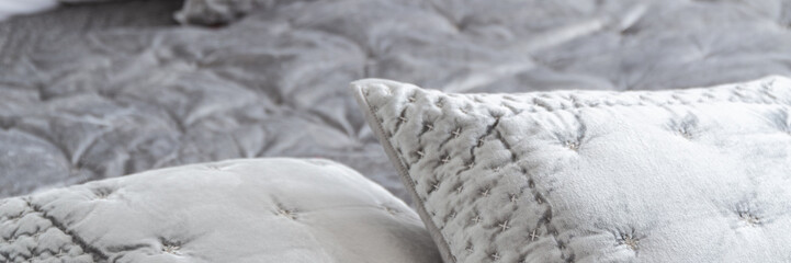 Panorama and close-up on elegant grey pillows with decorative trim on bed in bedroom interior. Real photo