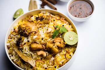 Delicious spicy chicken biryani in bowl over moody background, it’s a popular Indian and Pakistani food.