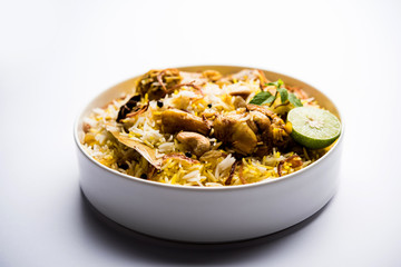 Delicious spicy chicken biryani in bowl over moody background, it’s a popular Indian and Pakistani food.