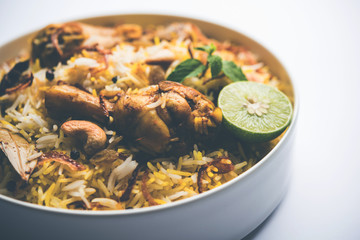 Delicious spicy chicken biryani in bowl over moody background, it’s a popular Indian and Pakistani food.