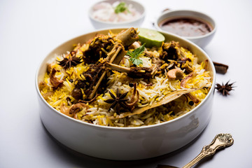 mutton or lamb biriyani with basmati rice, served in a bowl over moody background.