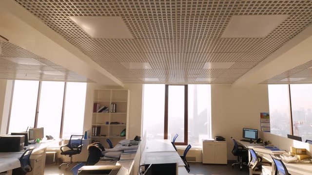 Large view of call center outside working hours. Modern empty office with open plan and large windows. Off-hours in office overlooking the skyscrapers on sunny day