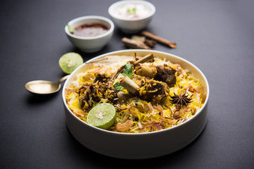 mutton or lamb biriyani with basmati rice, served in a bowl over moody background.