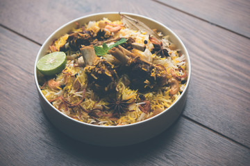 mutton or lamb biriyani with basmati rice, served in a bowl over moody background.
