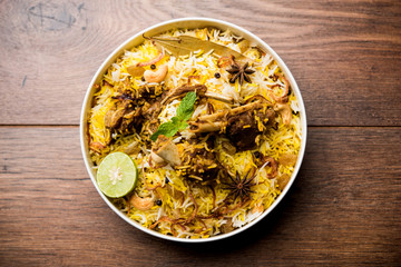 mutton or lamb biriyani with basmati rice, served in a bowl over moody background.