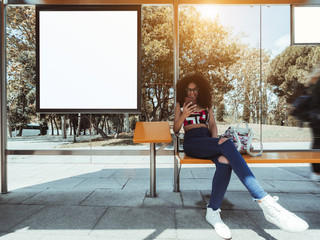 A smiling caucasian female with bulky curly hair and in eyeglasses is sitting inside of the outdoor...