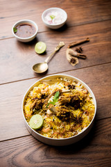 mutton or lamb biriyani with basmati rice, served in a bowl over moody background.