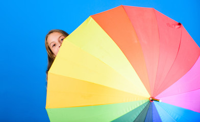 Color your life. Girl cheerful hide behind umbrella. Colorful umbrella accessory. Weather forecast concept. Stay positive though rainy day. Brighten up life. Kid peek out colorful rainbow umbrella