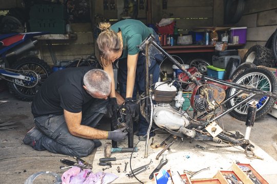 Mechanics repairing motorcycle in workshop