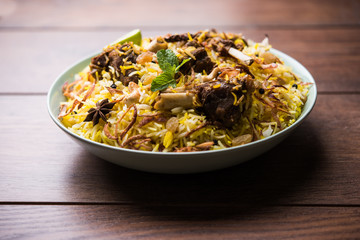 mutton or lamb biriyani with basmati rice, served in a bowl over moody background.