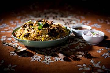 mutton or lamb biriyani with basmati rice, served in a bowl over moody background.