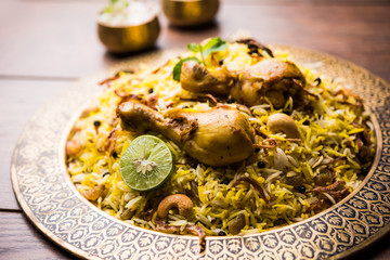 Delicious spicy chicken biryani in bowl over moody background, it’s a popular Indian and Pakistani food.