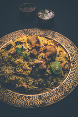 Delicious spicy chicken biryani in bowl over moody background, it’s a popular Indian and Pakistani food.