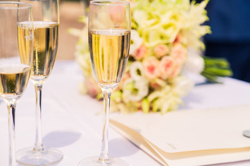 Fresh flowers collected in bouquets in bright colors. Lies on the table. Wedding bouquet in rustic style. Gentle roses for the bride. A glass of alcoholic champagne. For the ceremony and important day