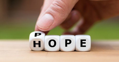 Hand is turning a dice and changes the word "hope" to "pope"