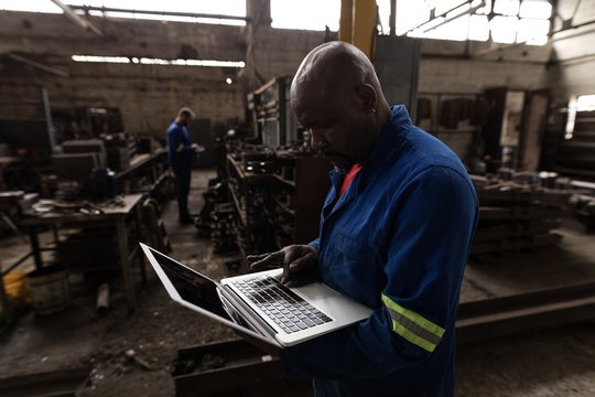 Blacksmith using laptop in workshop - Powered by Adobe