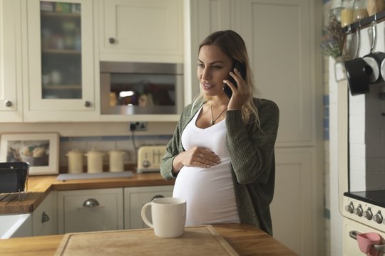 Pregnant young woman with bleached hair talking on smartphone