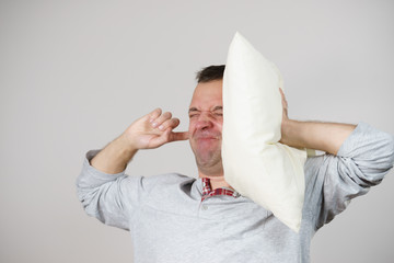 Sleepy man with pillow closing his ear