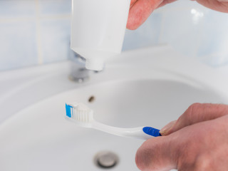 Person putting toothpaste on toothbrush