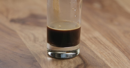 Closeup espresso in glass with cold water on wood table