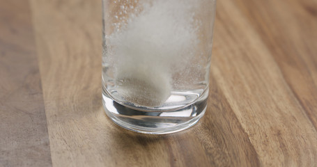 effervescent tablet in glass of water on wood table