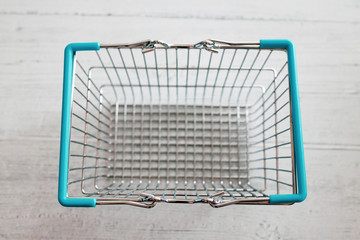 empty shopping basket on light-coloured wooden table