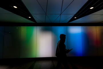 Young man walking using phone in futuristic modern sci-fi moody dark tunnel background city London...