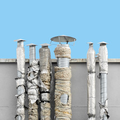 Close up of set of ventilation chimneys with damaged isolation against blue sky