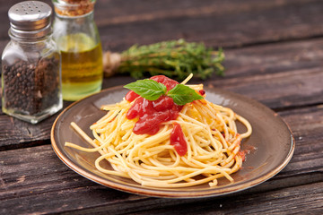 spaghetti with ketchup and Basil on dark wooden background