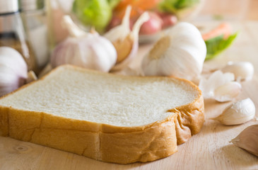 Soft bread with garlic on hopping board in kitchen courter