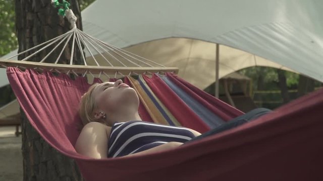 Sweet girl resting in a hammock in the park