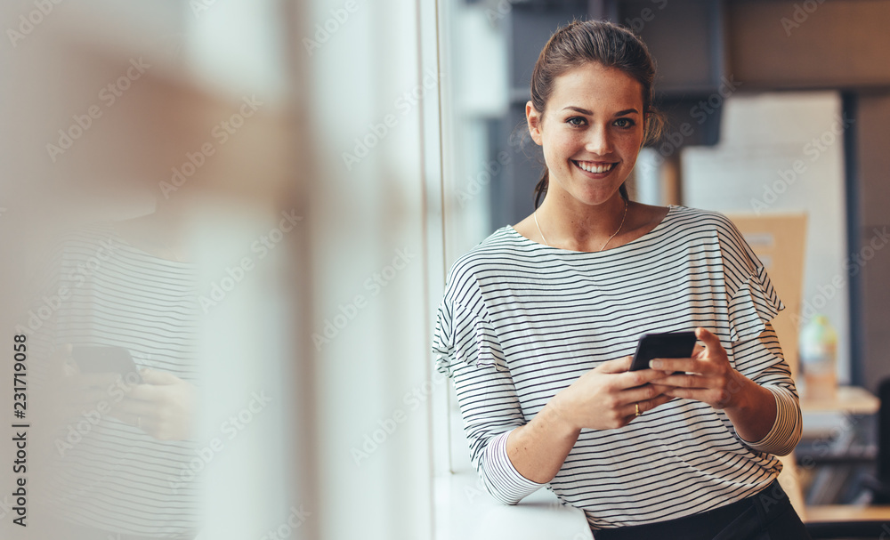 Wall mural businesswoman in office using a cell phone