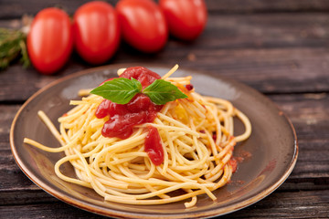 spaghetti with ketchup and Basil on dark wooden background