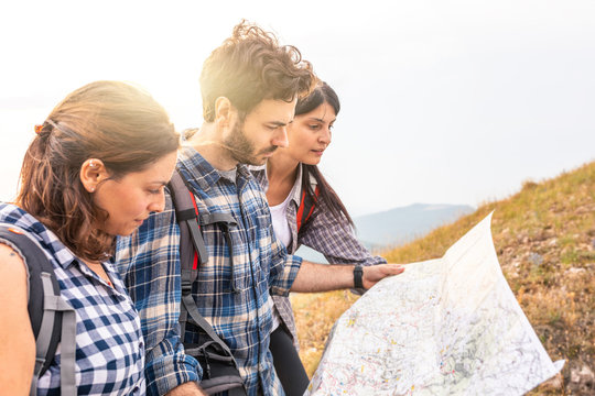 Group Of People Hiking And Looking At Map During Their Adventure