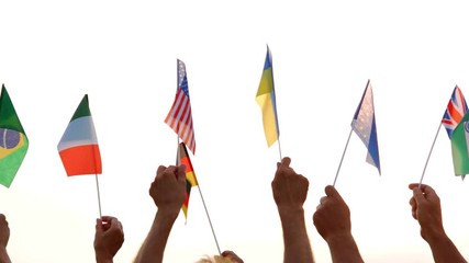People raised flags of different countries. Many human hands holding flags of their countries outdoors. Cooperation between nations.