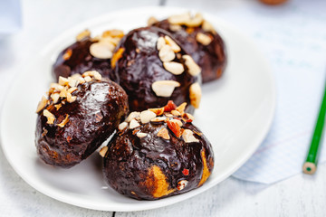 Cookie balls with chocolate glaze and walnuts on white plate. Close up