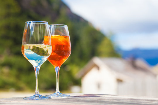 Chilled aperol spritz and prosesso glasses over mountains background