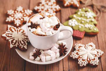 Obraz na płótnie Canvas Christmas or new year background. A Cup of festive hot chocolate or cocoa with marshmallows and traditional handmade gingerbread on the table. The concept of advertising cocoa drink. 
