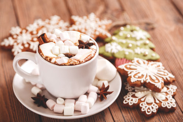 Christmas or new year background. A Cup of festive hot chocolate or cocoa with marshmallows and traditional handmade gingerbread on the table. The concept of advertising cocoa drink. 