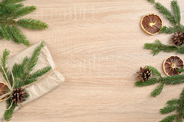 Christmas composition. Spruce branch with cones, slices of dry orange and a gift. Free space under the text. Light background. View from above.