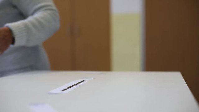Video of a person casting a ballot at a polling station, during elections.